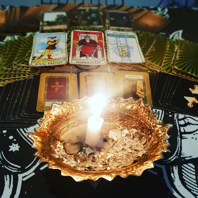 Altın bir kâsede mum, çevresinde sıcak ışıkta duran ve yatan tarot kartları